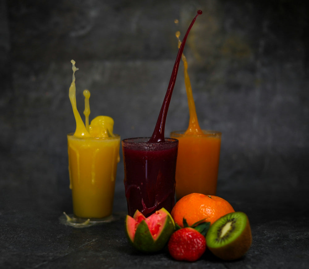 Three colorful smoothies in glasses next to fresh fruit, comparing smoothie boxes